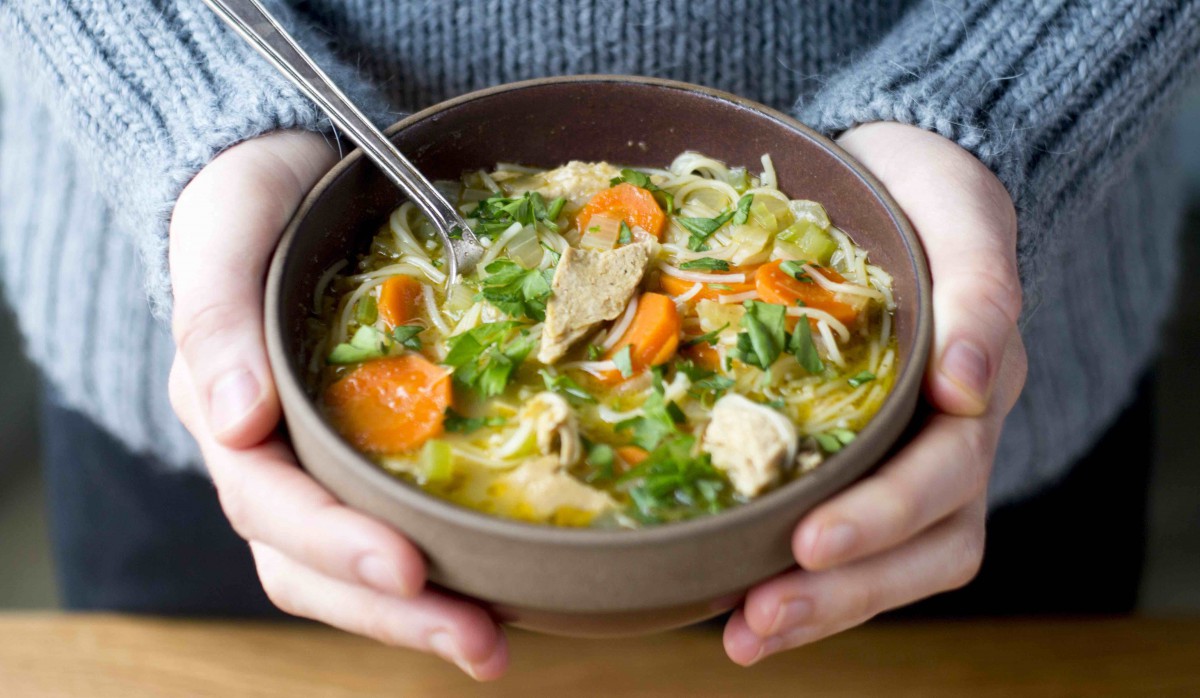 Hands holding bowl of plant-based soup