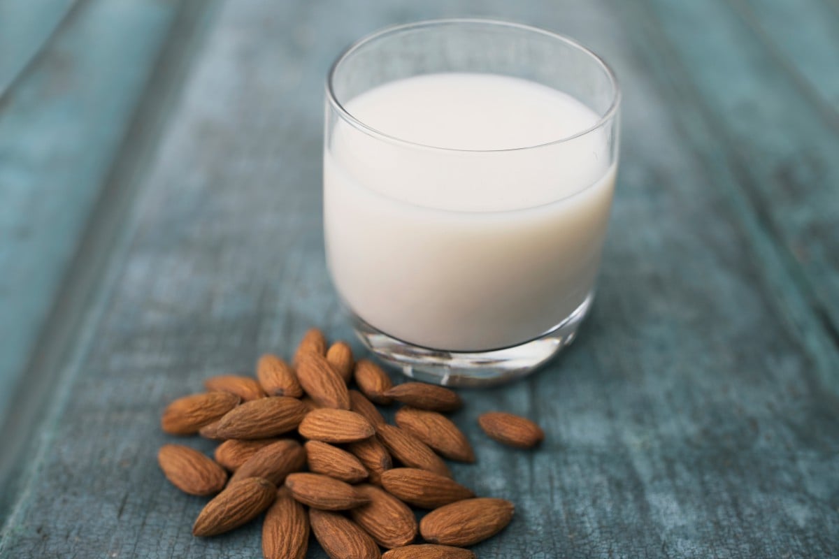 Glass of milk next to almonds