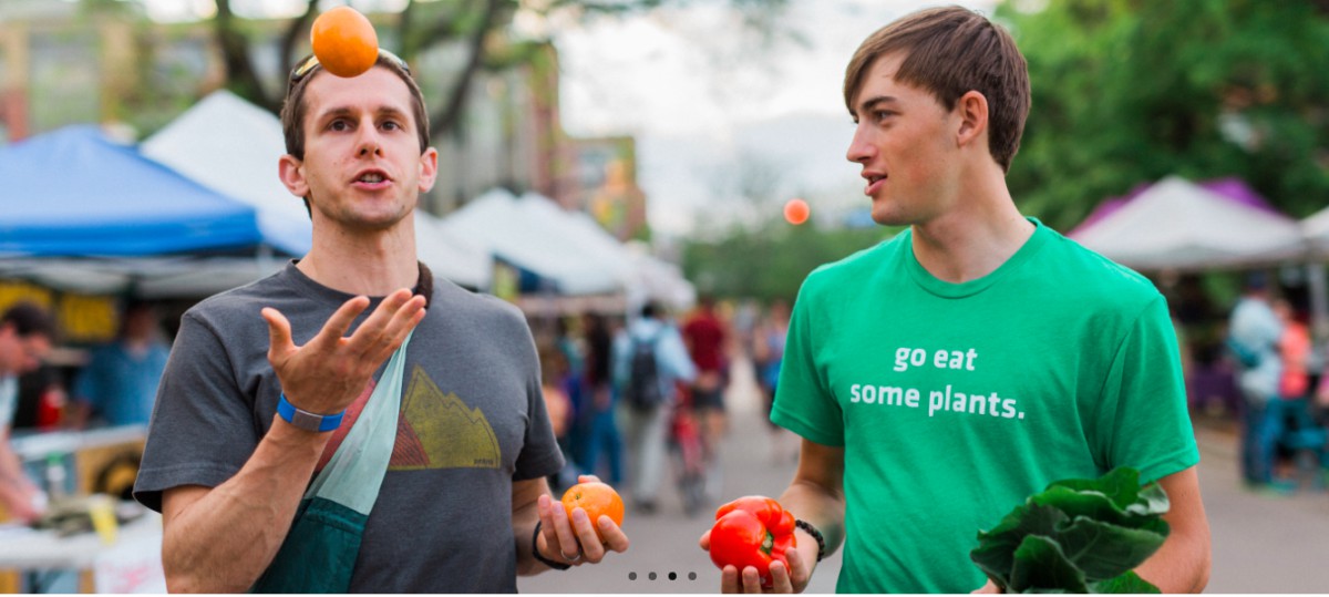 Two people holding fruits and vegetables talking