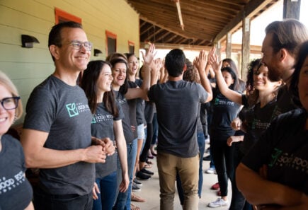 A group of gfi employees gathered in two rows giving out high fives and smiles