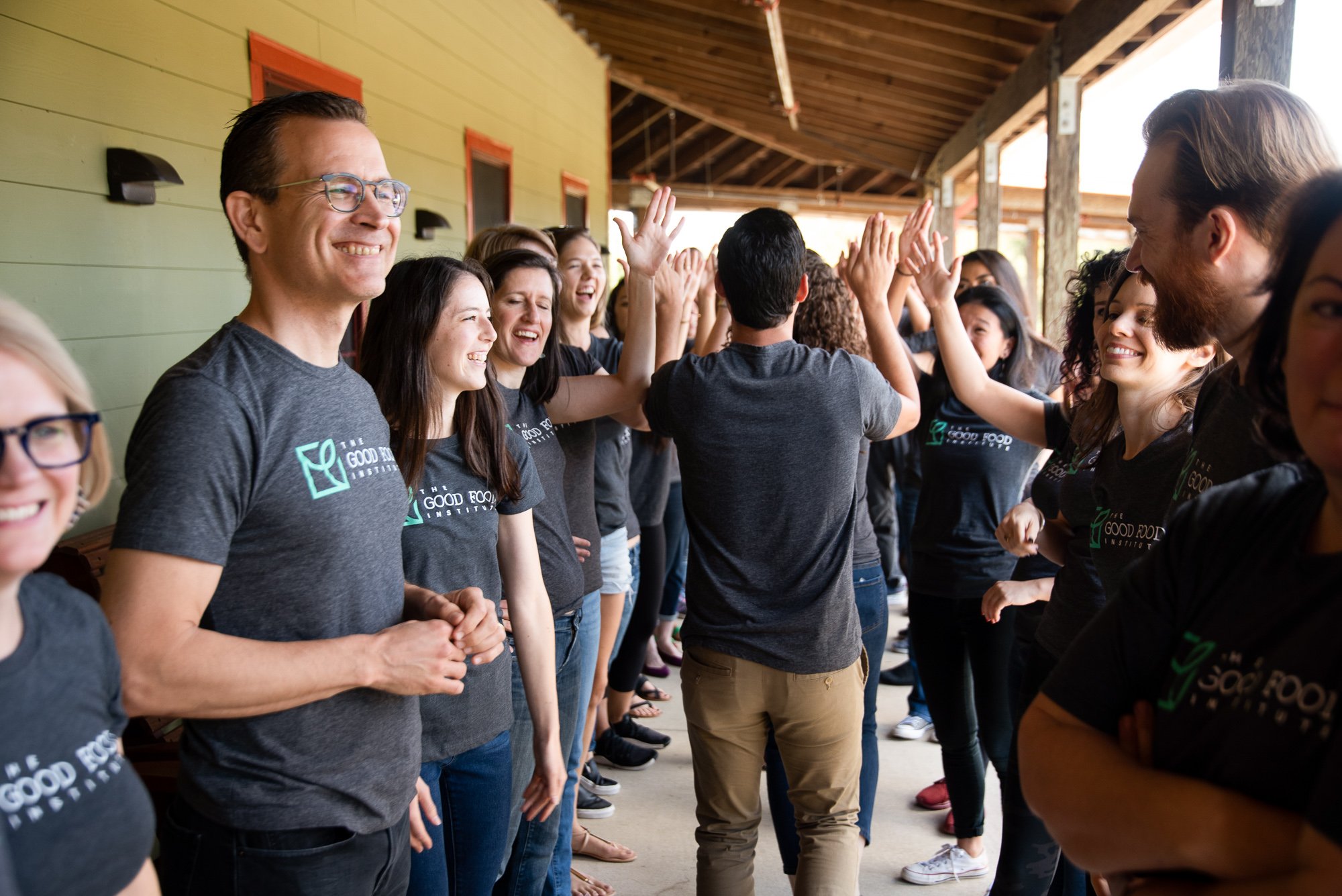 A group of gfi employees gathered in two rows giving out high fives and smiles