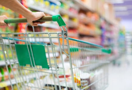 Close up of a grocery cart being pushed down an aisle