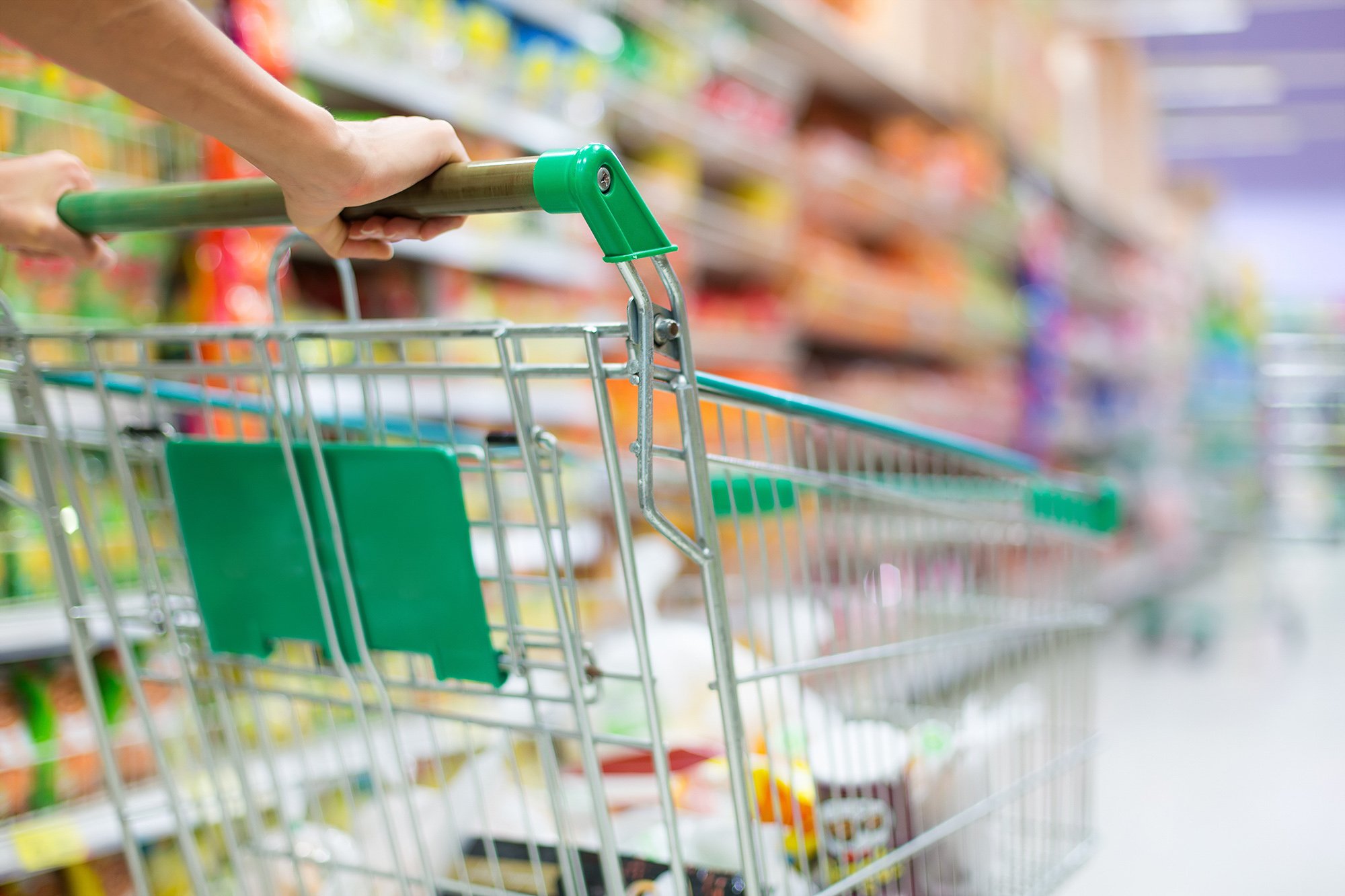 Close up of a grocery cart being pushed down an aisle