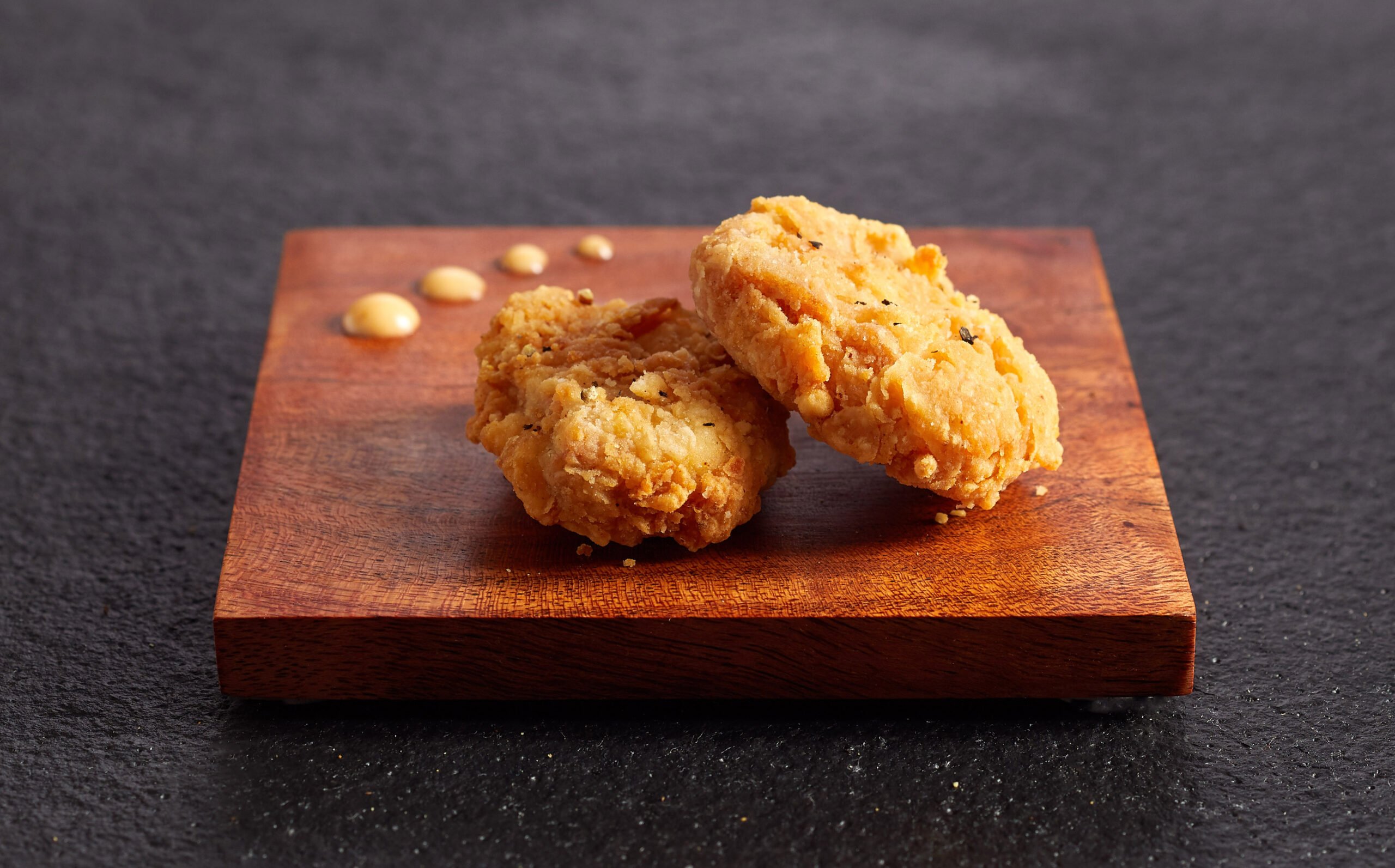 Two chicken bites on wood slate