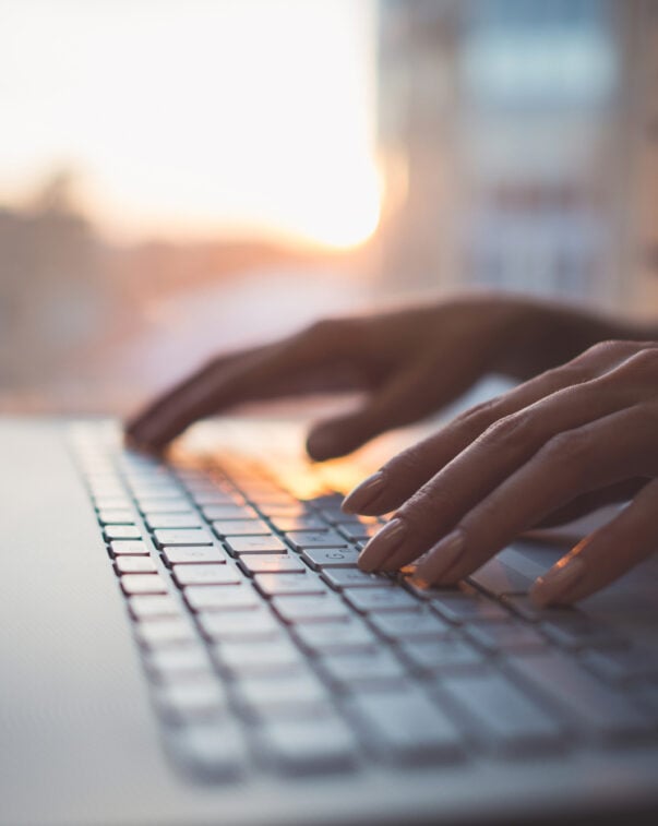 Hands typing on a laptop computer keyboard, representing mooc concept for cultured meat and plant-based meat science.