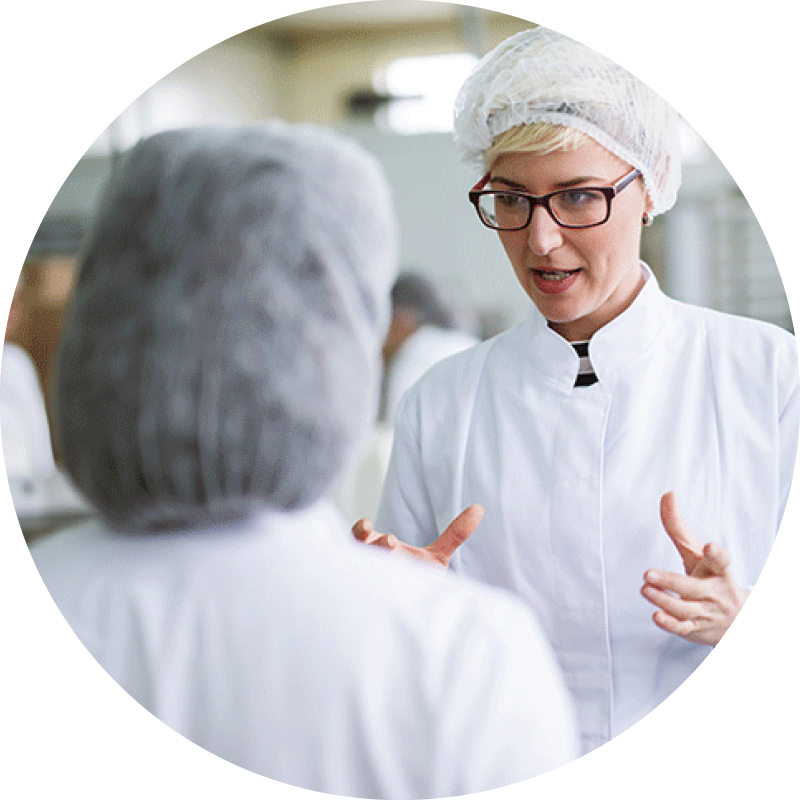 Two female workers discussing food quality while standing in a packing plant