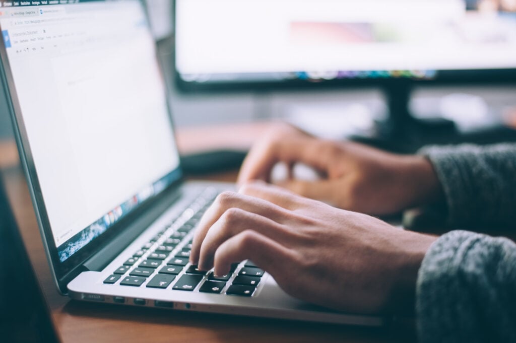 Closeup of person’s hands typing on a laptop computer