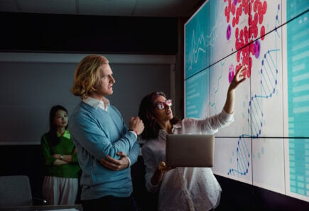 Scientists looking at a screen displaying animal cells and a DNA double helix