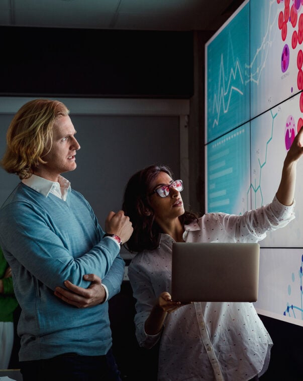 Scientists looking at a screen displaying animal cells and a dna double helix