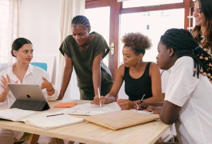 A group of entrepreneurs gathered around a table meeting about their business plan