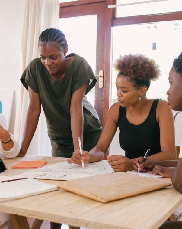 A group of entrepreneurs gathered around a table meeting about their business plan