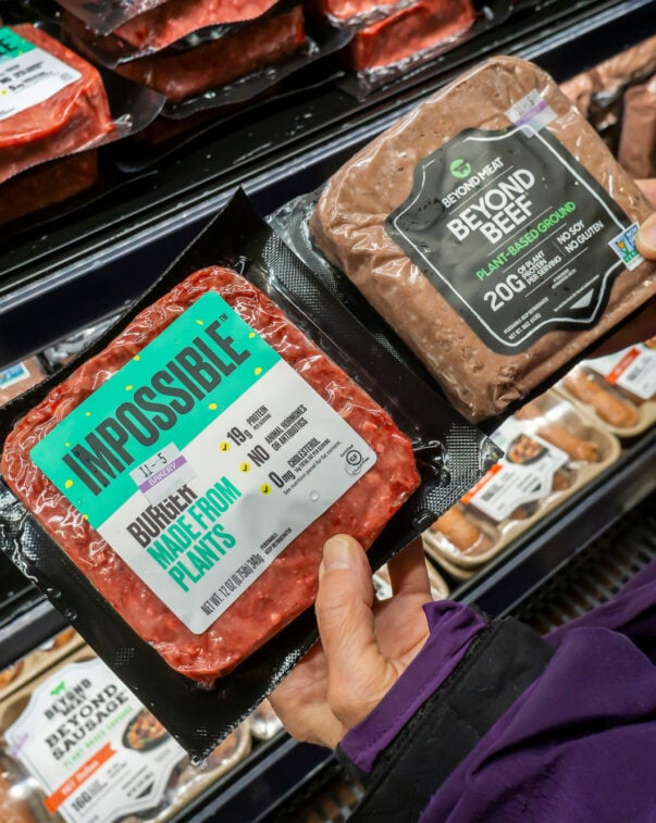 A shopper compares plant-based meat products in a supermarket aisle