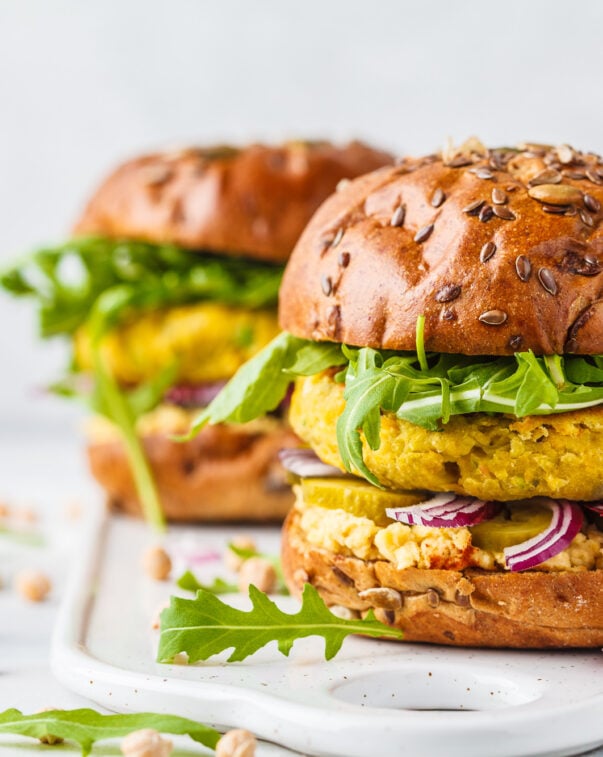 Plant-based burgers topped with arugula on a white stone counter