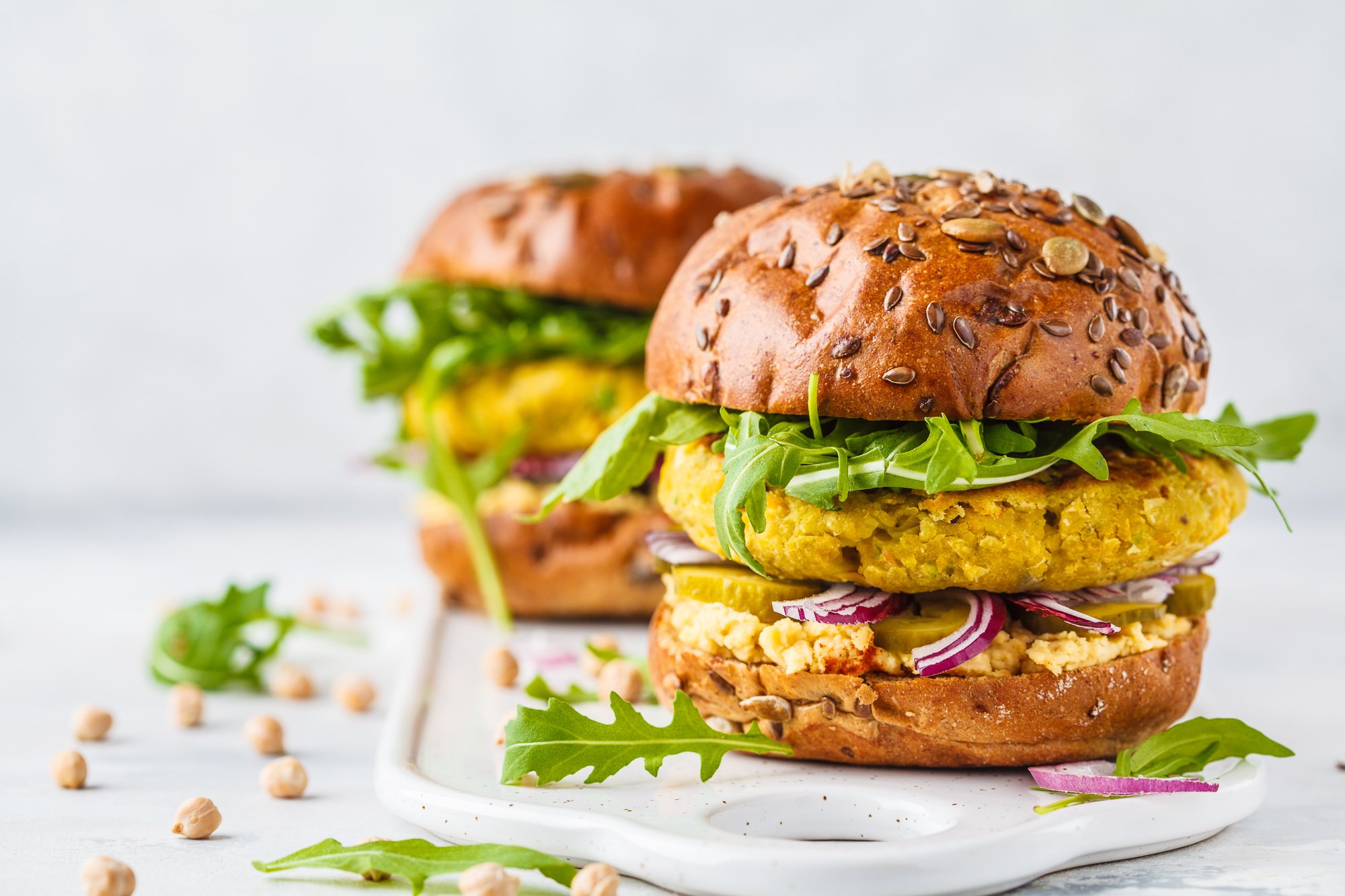 Plant-based burgers topped with arugula on a white stone counter