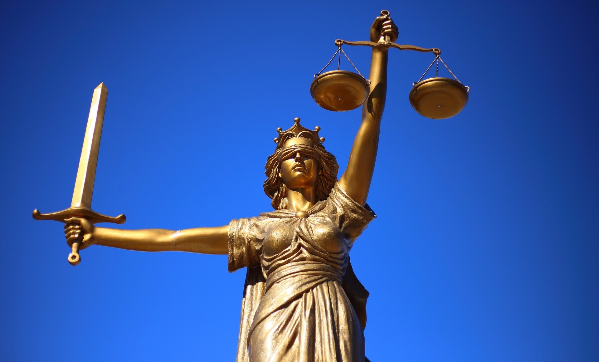 Bronze scales of justice with blue background