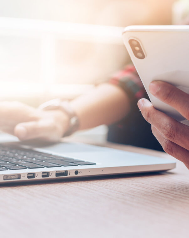 Close up of a man using a cell phone and laptop