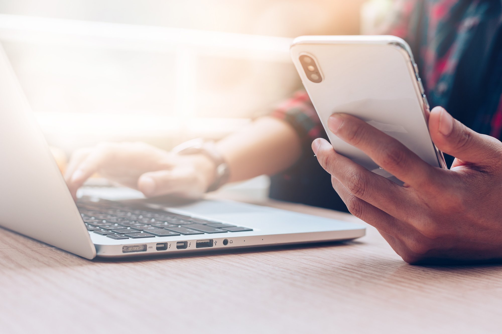 Close up of a man using a cell phone and laptop