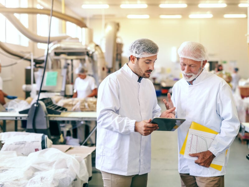 Two workers in sterile clothing inside a food manufacturing facility