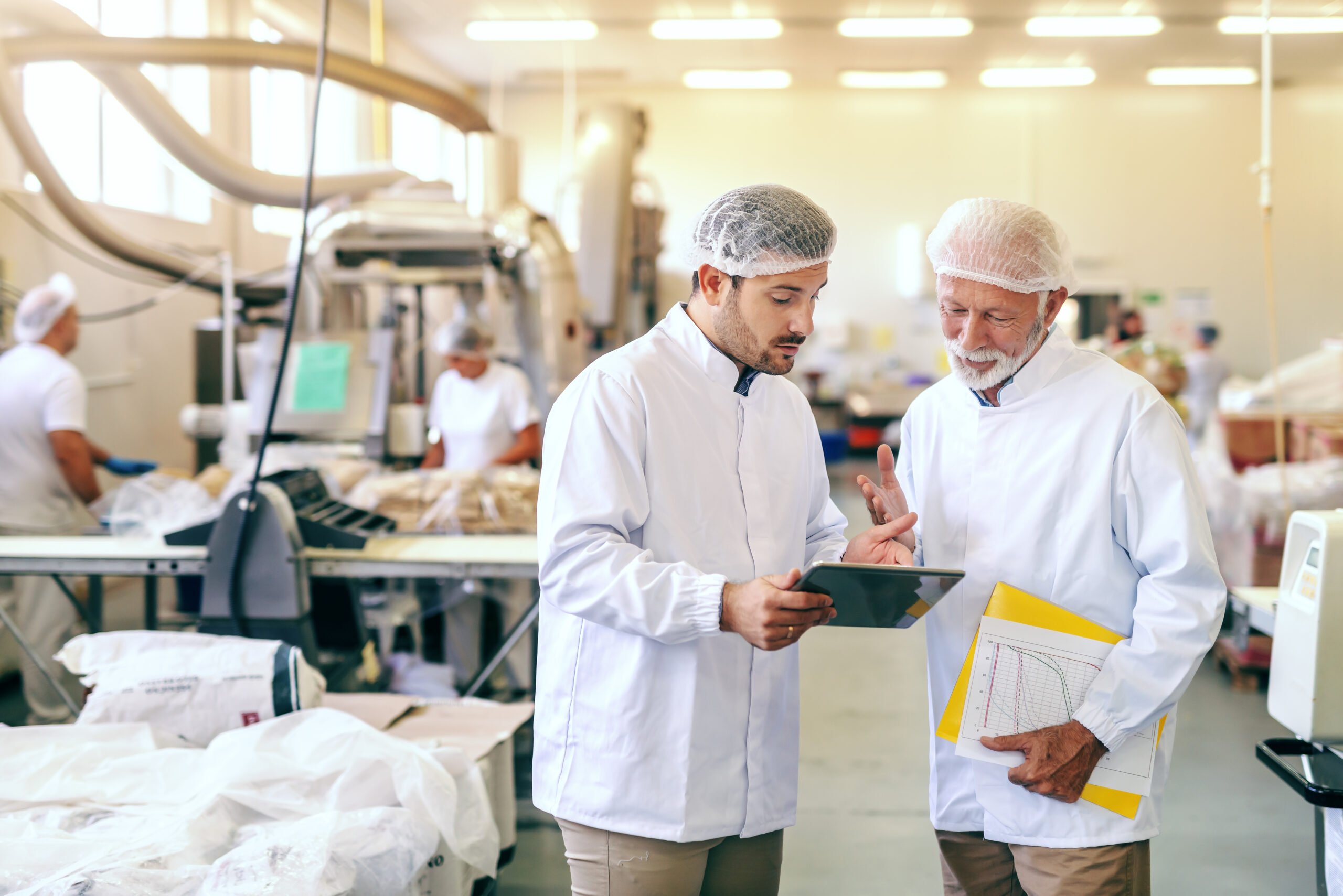 Two workers in sterile clothing inside a food manufacturing facility