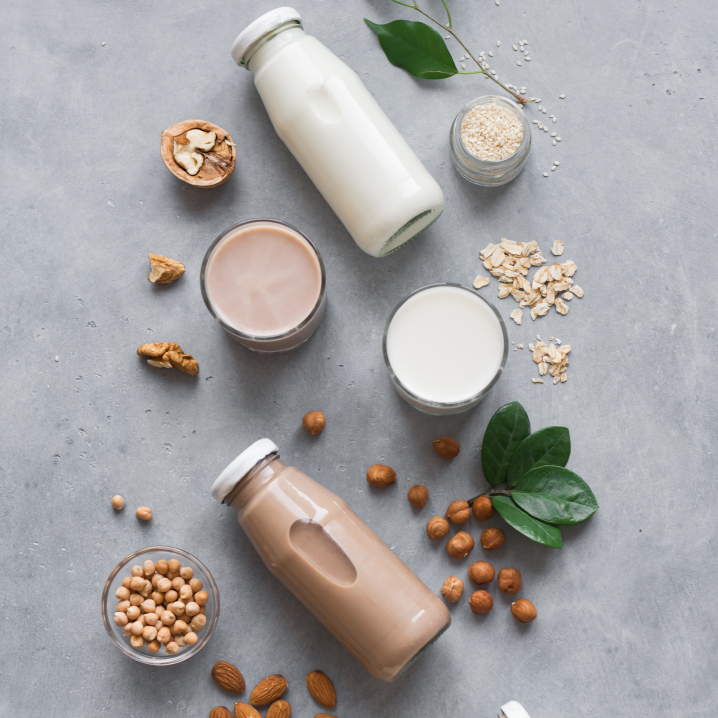 Plant-based retail market overview 13 Plant based milk bottles and ingredients artistically arranged on a gray stone background