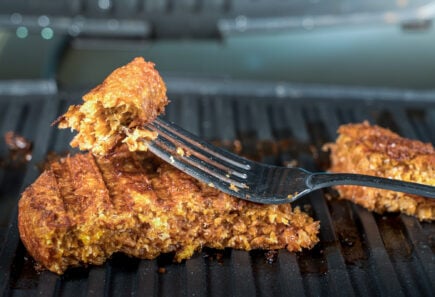 Fork full of seared plant based meat on a grill