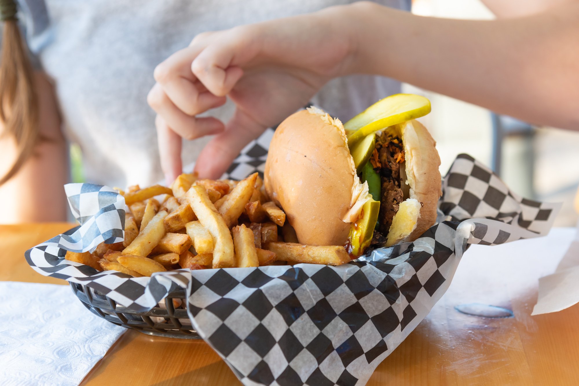 Plant-based burger with fries on checkered paper in a food service context