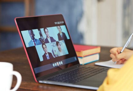 Remote conference call on a red laptop at a cafe