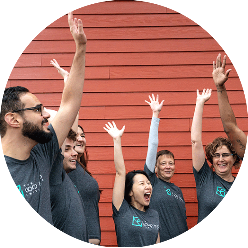 A group of gfi staff celebrating with arms in the air in front of a red wall