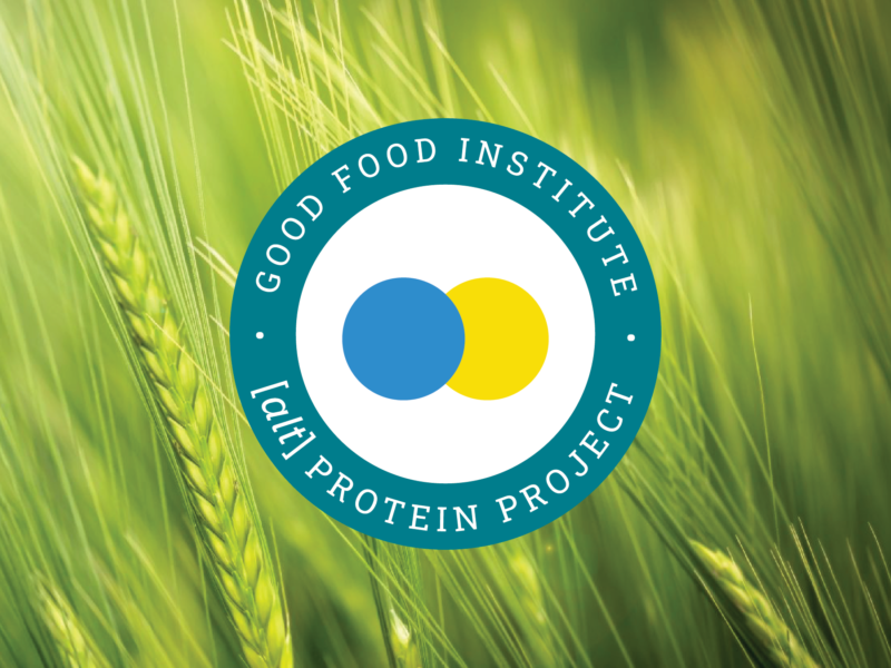 Alt protein project badge on a in front of a field of green wheat