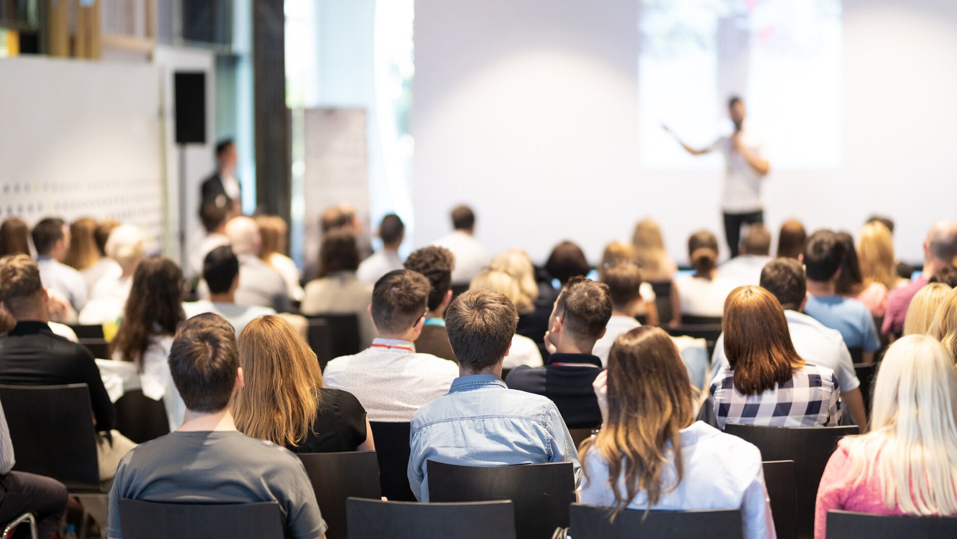 Room full of seated people listening to someone speak