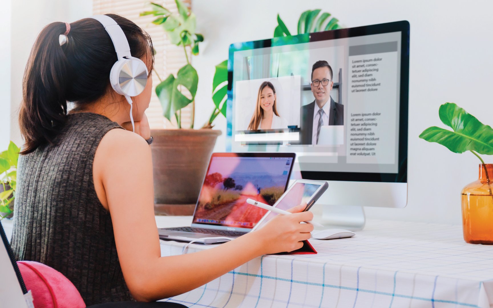 Person wearing headphones looking at monitor while holding tablet