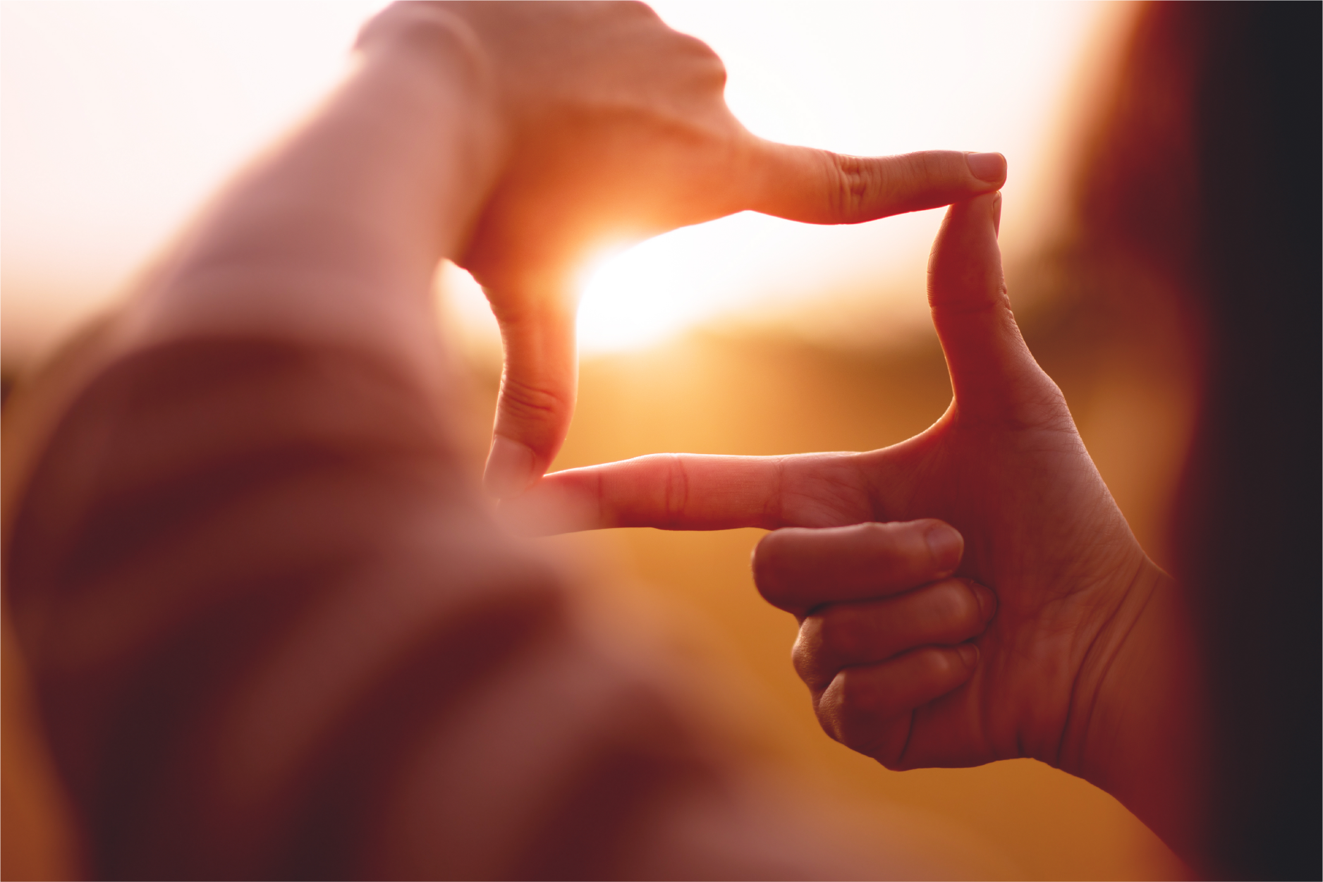 Person's fingers framing sun