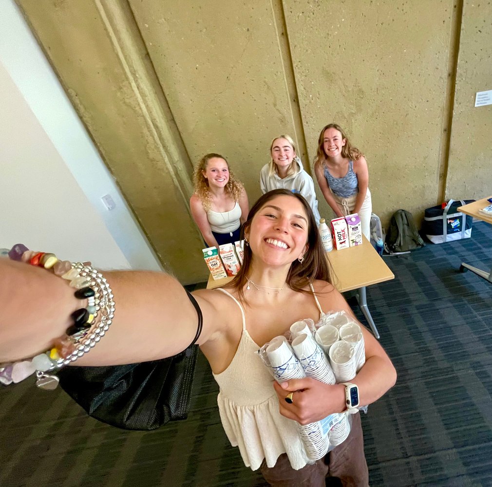 Alt protein project students ellie, hannah, gianna, and chloe setting up a plant-based milk and cookies sampling.