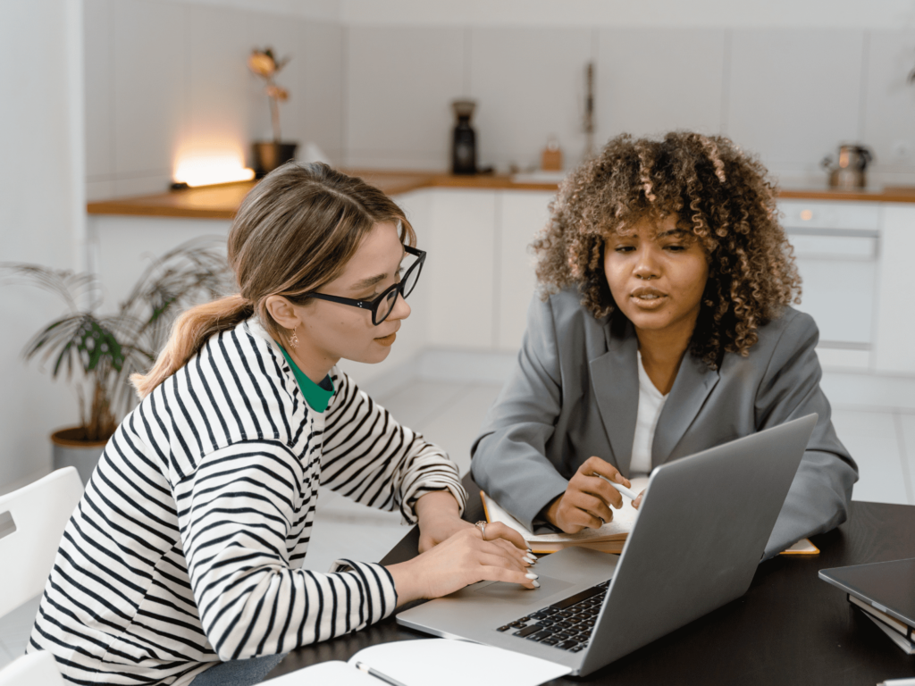 A photo of two business people meeting and looking at a laptop screen together