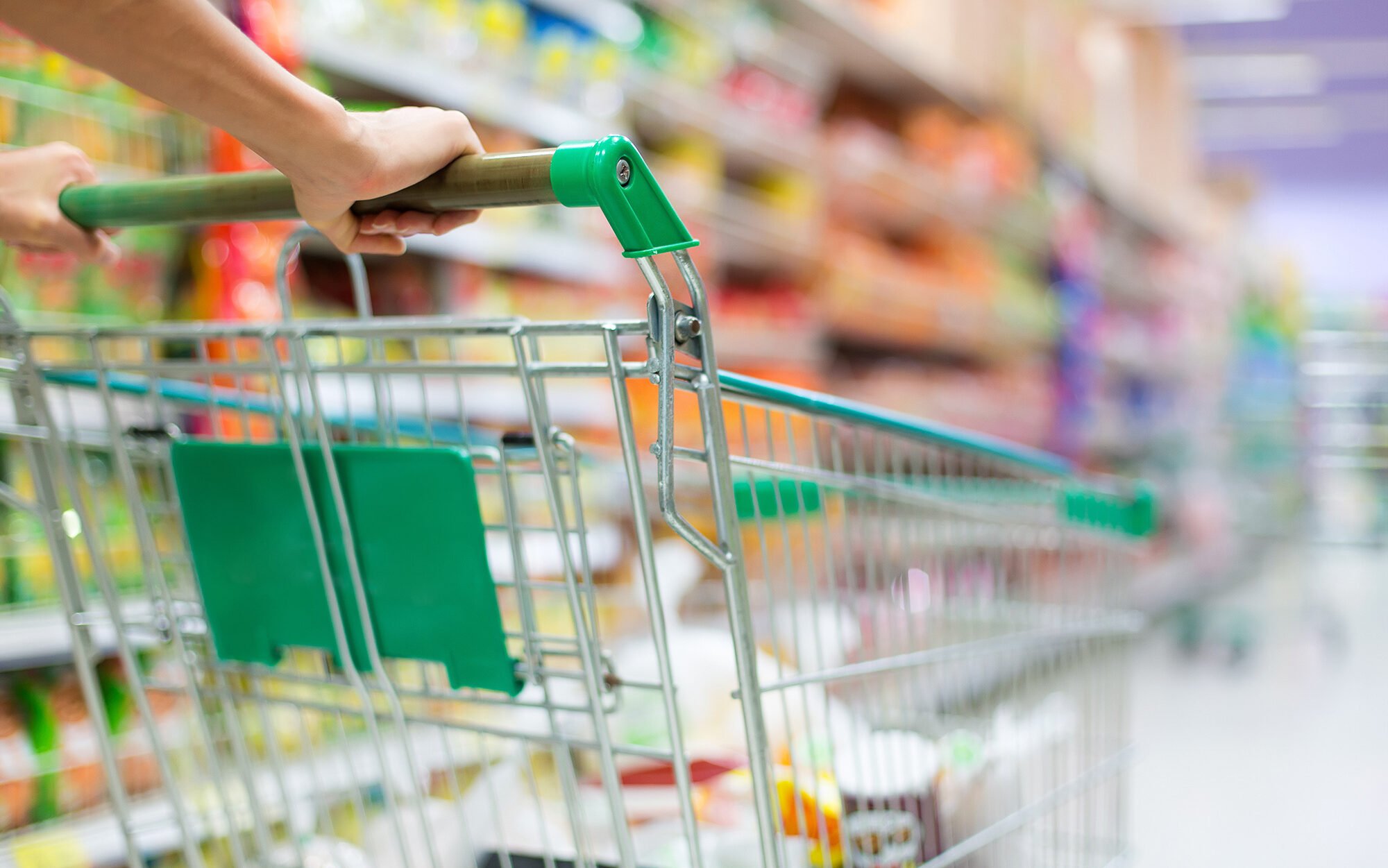 Close up of a grocery cart being pushed down an aisle