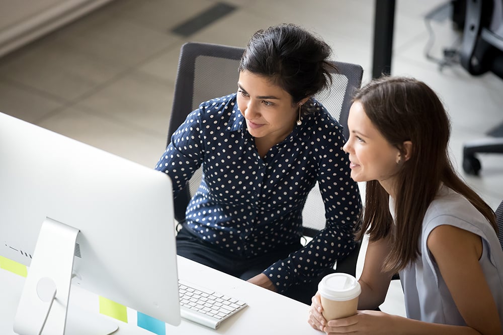 Two colleagues looking at a computer screen together in an office