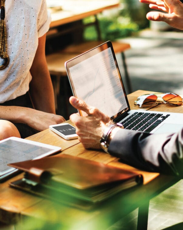 Two industry professionals looking at a laptop at a cafe table