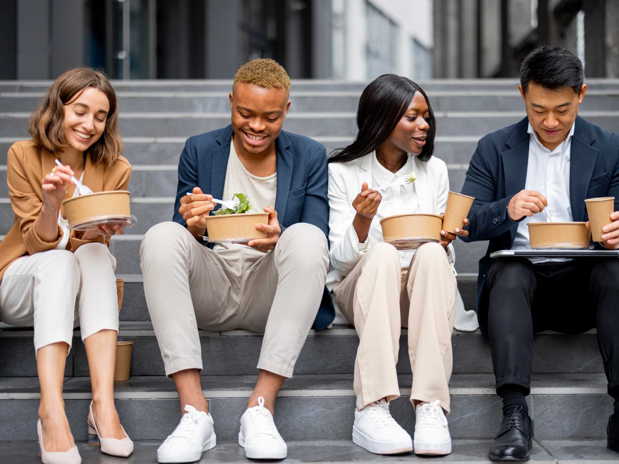 A small group of people sit on some steps while eating food