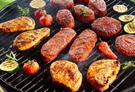 Plant-based steaks, filets, chicken breasts cooking on a grill