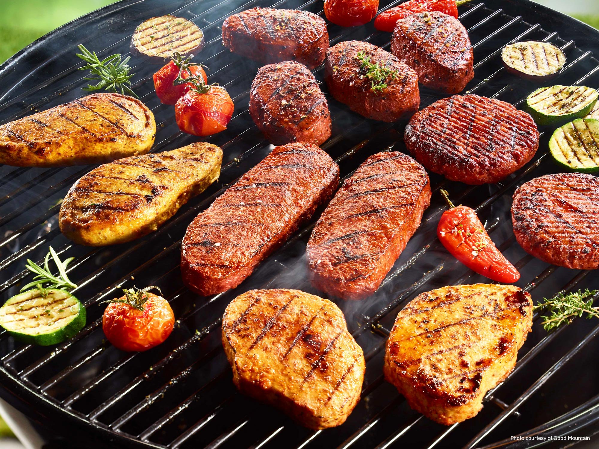 Plant-based steaks, filets, chicken breasts cooking on a grill