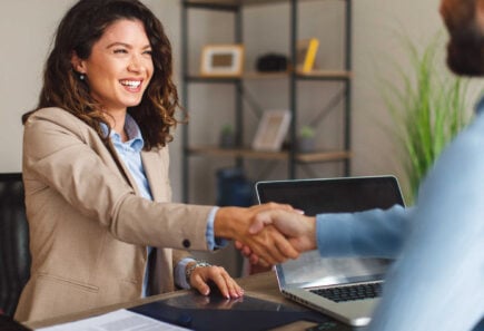 Smiling woman in blazer shaking hands during a meeting