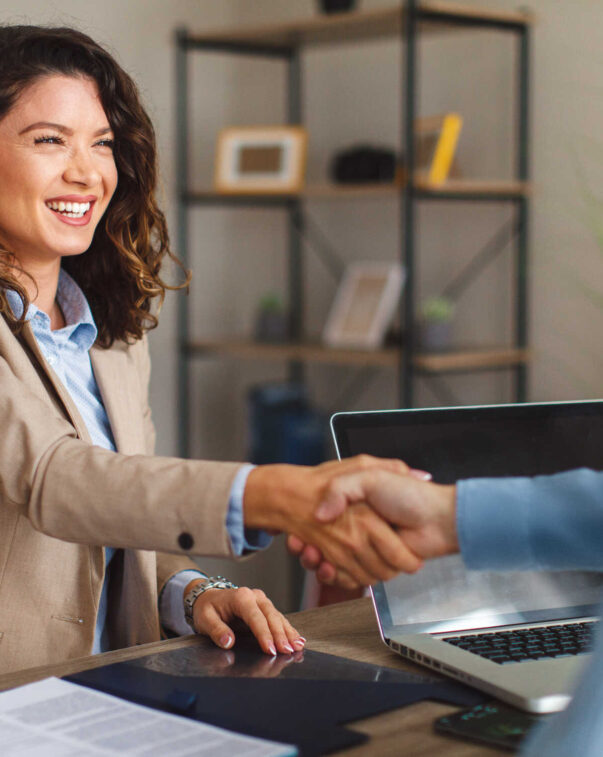 Smiling woman in blazer shaking hands during a meeting