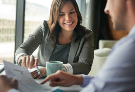 Smiling woman discussing document with colleague