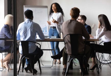 Businesswoman giving presentation to diverse colleagues in modern conference room