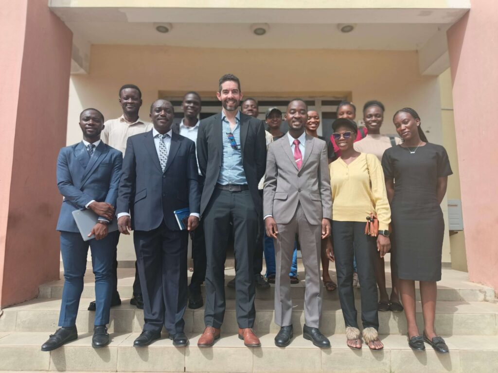 Members and executives of the University of Ibadan Alt Protein Project standing with their faculty advisor and a GFI Europe representative outside a campus building.