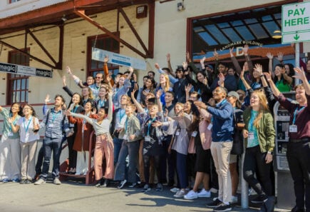 Group of people outside a building, smiling and waving