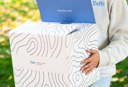 Cultivated meat lca/tea report analysis 11 Person holding tufts university cellular agriculture box