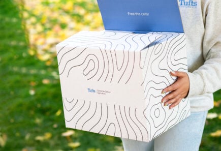 Blog 1 Person holding box with tufts branding
