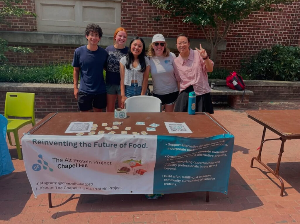 Five students stand behind an informational table