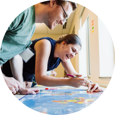 Two smiling people leaning over a table and writing